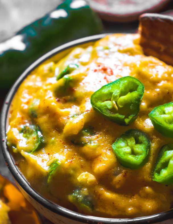 cheesy jalapeno dip in a bowl with minced jalapenos on top 