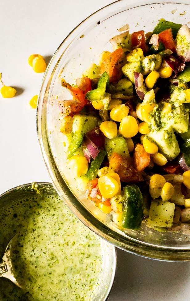 Half bowl of summer corn salad with cilantro lime dressing beside