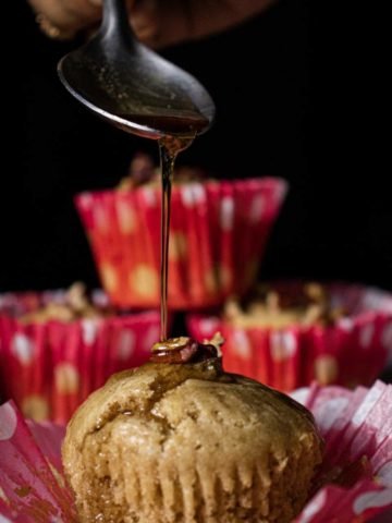 Maple Glazed Apple Cider Pecan Muffins with a spoon pouring maple syrup on the muffin
