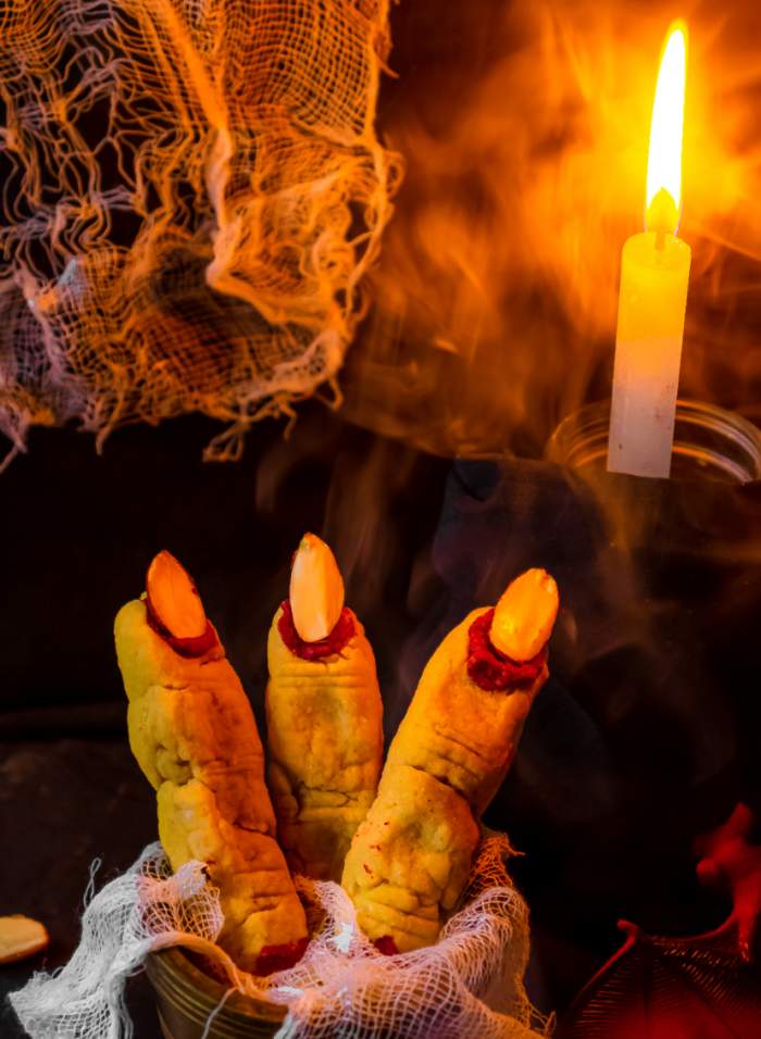 Witchs fingers with candle and bandage in the background
