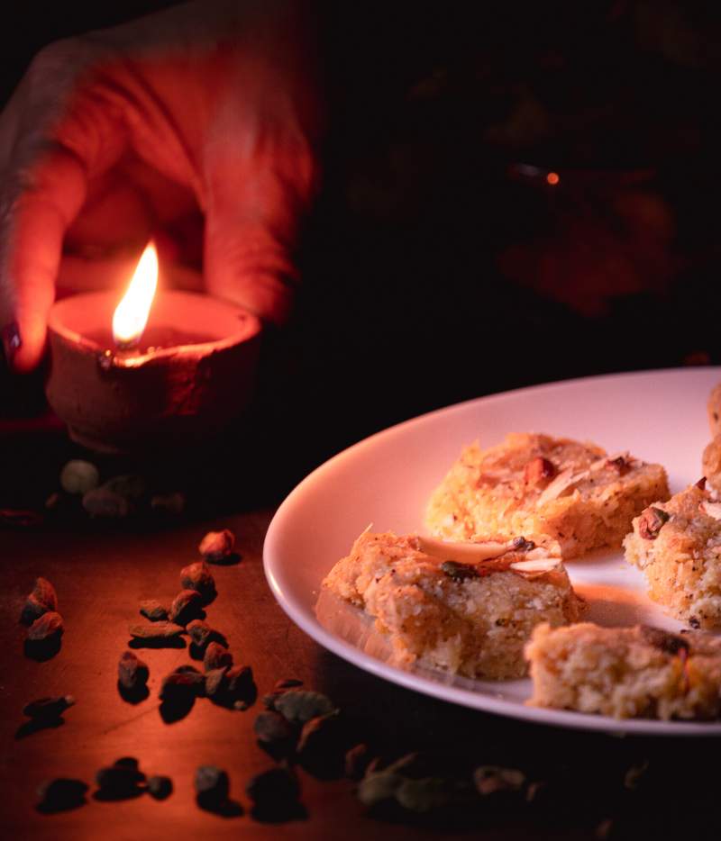 Placing a earthern lamp beside a plate full of apple coconut barfi