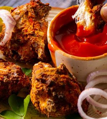 Dipping southern fried chicken in hot sauce