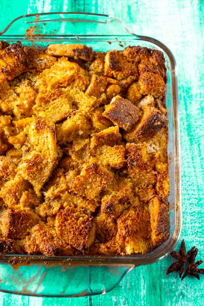 Pumpkin Bread Pudding kept on a cyan colored table with a star anise beside it 