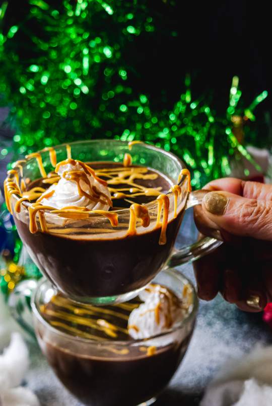 Vegan Peanut Butter Hot Chocolate in a cup near Christmas tree