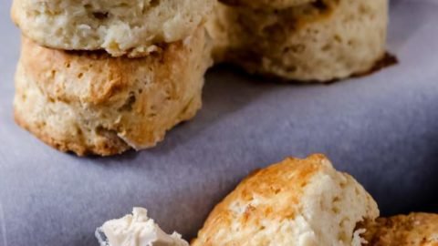 Biscuits stacked together on a white table with some bicuits on a black surface below