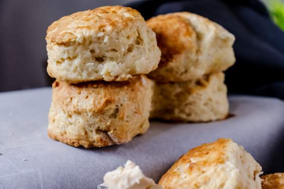 Southern Buttermilk Biscuits on a white surface with a butter knife with some butter on it