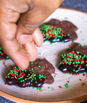 sprinkling red and green confetti on christmas cookies