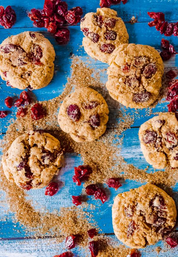 Cranberry Cream Cheese Snickerdoodles arranged on a blue table with cranberries