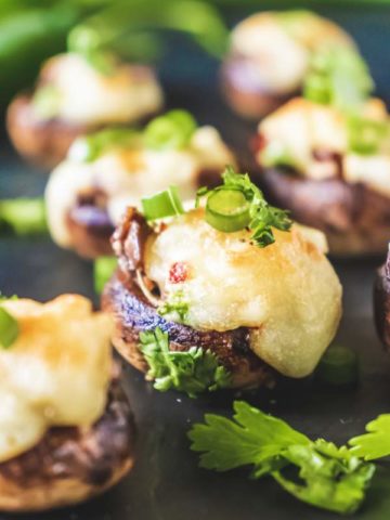 Cream Cheese Stuffed Mushrooms kept on a black table with many others blurred in the background