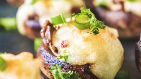 Cream Cheese Stuffed Mushrooms kept on a black table with many others blurred in the background