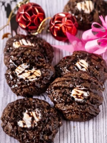 Hot Chocolate Cookies arranged on a white surface with a pink bow and red oranament in the back