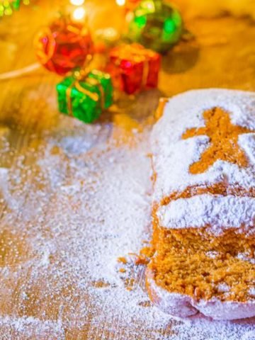 Moist Homemade Gingerbread Loaf on a wooden surface with powdered sugar gifts and ornaments on the top