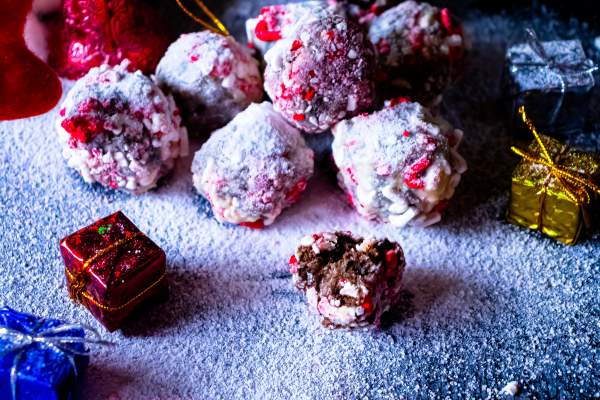 Peppermint Cheesecake Oreo Truffles aranged on a black background with one half eaten