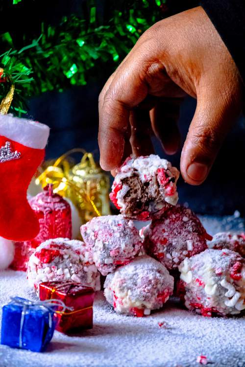 Peppermint Cheesecake Oreo Truffles with a hand keeping the last eaten truffle