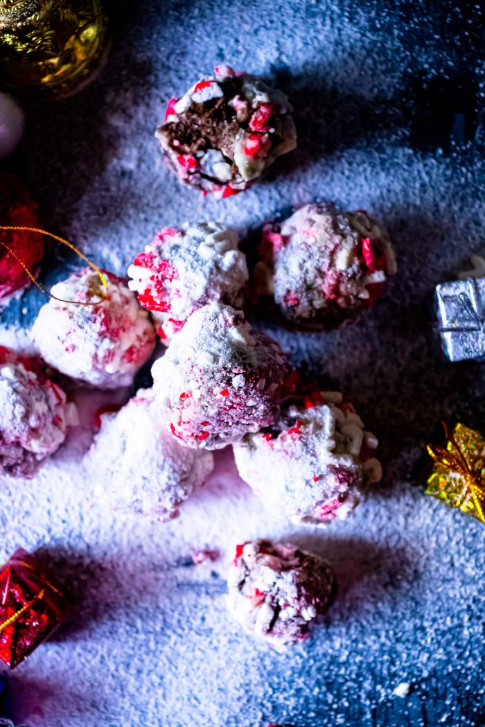 Peppermint Cheesecake Oreo Truffles arranged on a black background with sugar powder on top