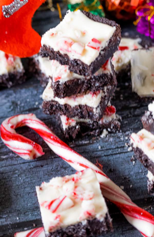 White Chocolate Peppermint Brownies stack with candy cane and one piece in front