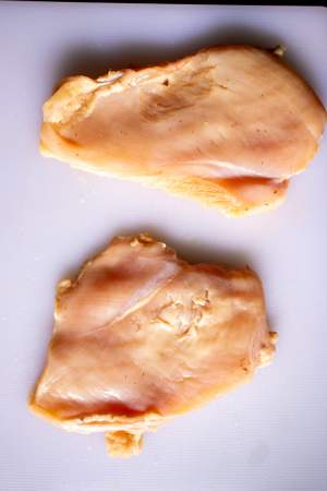 chicken breast on a white cutting board