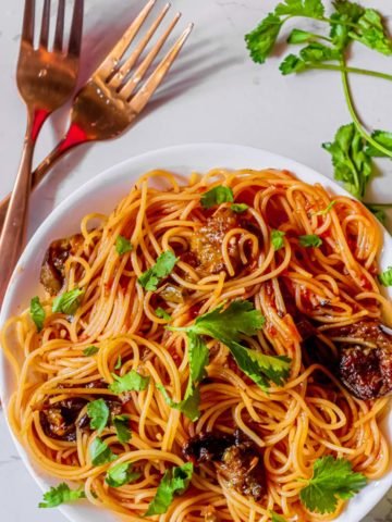 Pot of pasta alla norma on a white bowl with fork beside