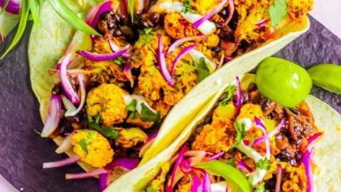 roasted cauliflower black bean tacos with red onions and lime on top