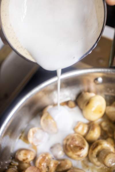 adding cream to Creamy Garlic Parmesan Mushrooms