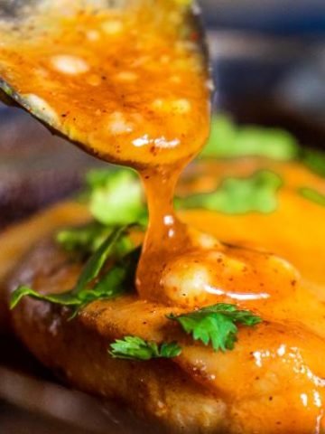 pouring sauce over honey mustard chicken breast