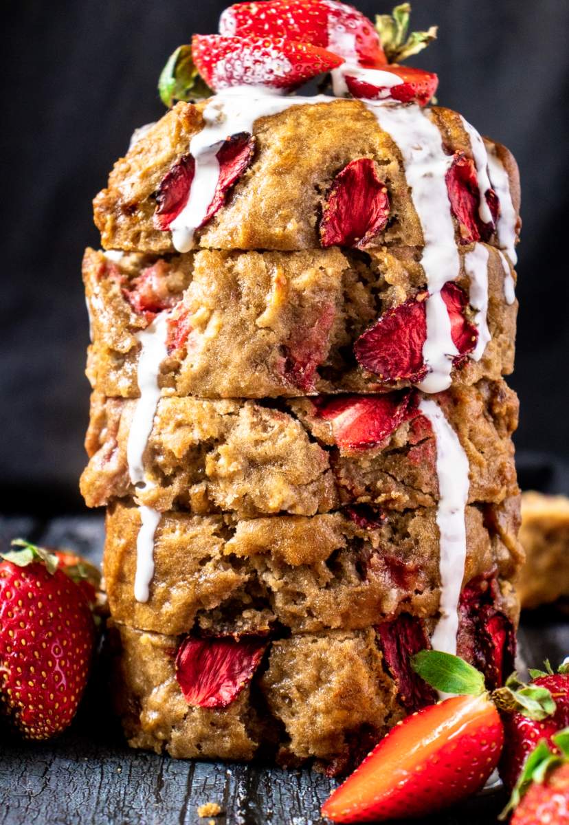 Strawberry Banana Bread with sugar glaze pouring on it and strawberries on it