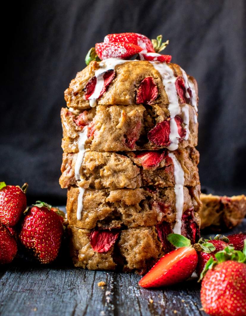 Strawberry Banana Bread on a black table with fresh strawberries