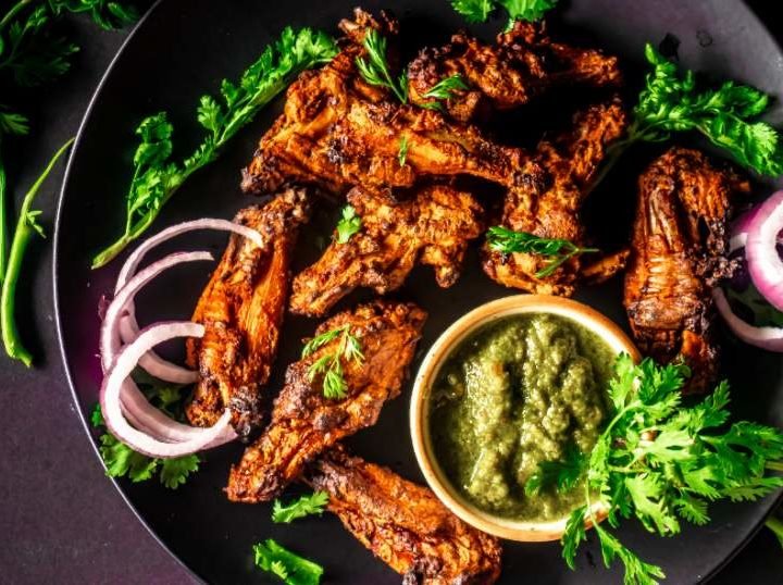 overhead view of tandoori chicken in a black plate