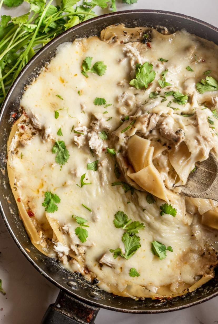white chicken skillet lasagna in a skillet with spatula