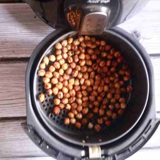 pulling out air fryer basket with roasted chickpeas from air fryer