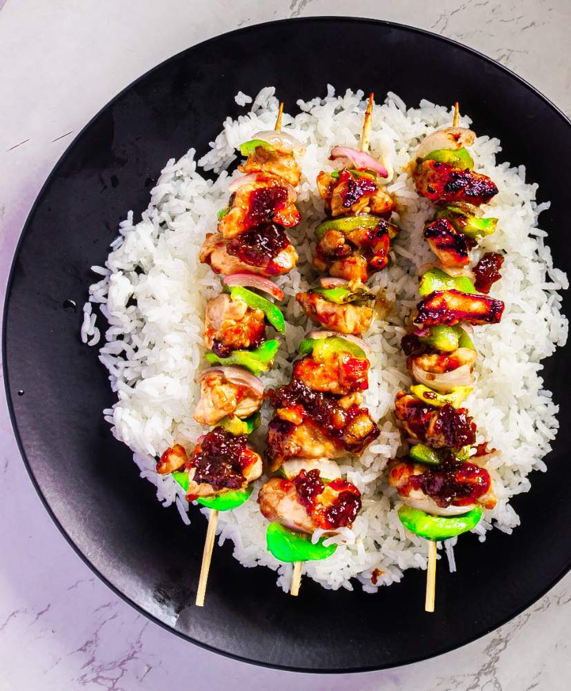 Grilled Teriyaki Chicken Skewers on a black plate with white rice