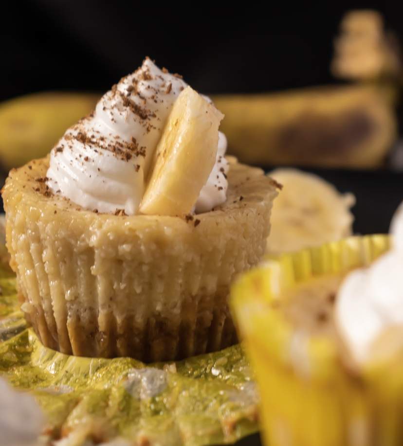 Mini Banana Cheesecake with a slice of banana attached to whipped cream frosting