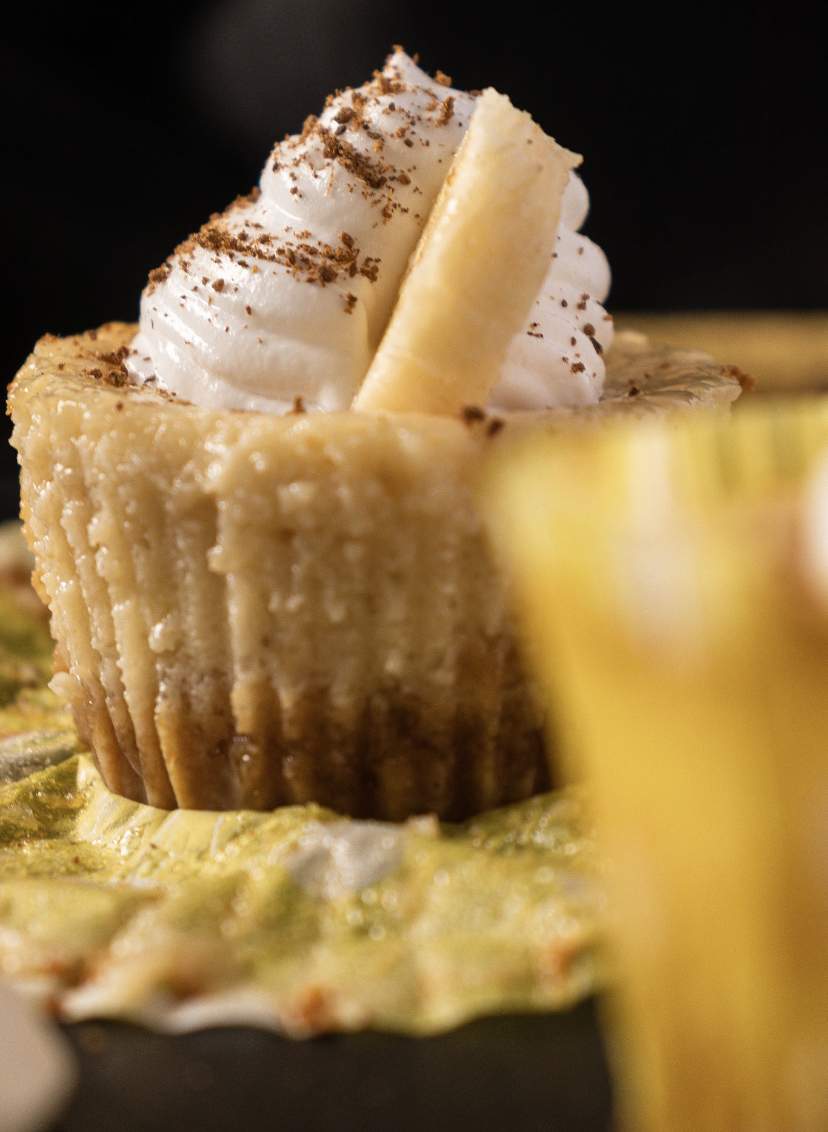 Mini Banana Cheesecakes with a slice of banana attached to whipped cream frosting