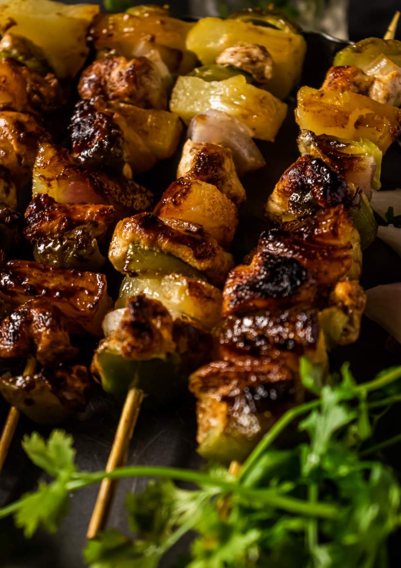 BBQ Pineapple Chicken Kabobs kept in a black plate with cilantro