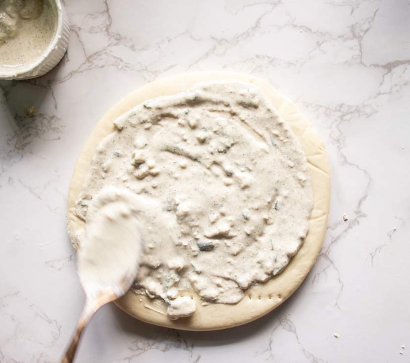 layering blue cheese dressing over pizza base