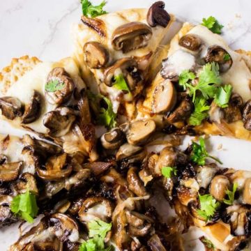Mushroom Pizza with parsley on top cut in slices and arranged on a white table