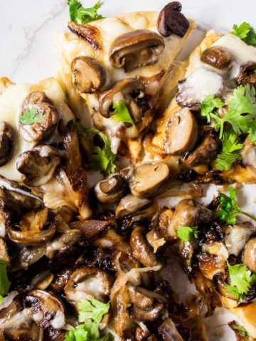 Mushroom Pizza with parsley on top cut in slices and arranged on a white table