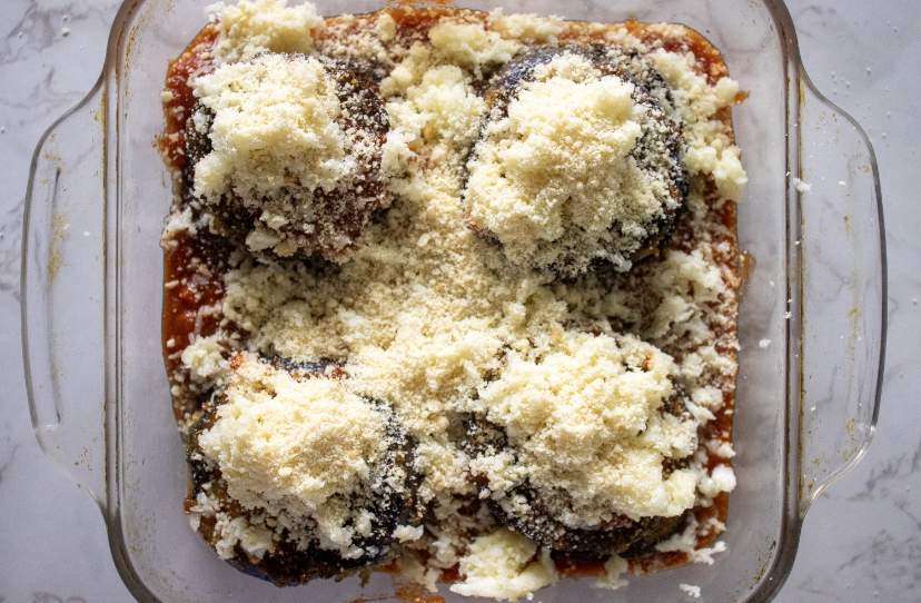 topping eggplant parmesan with mozzarella and parmesan cheese