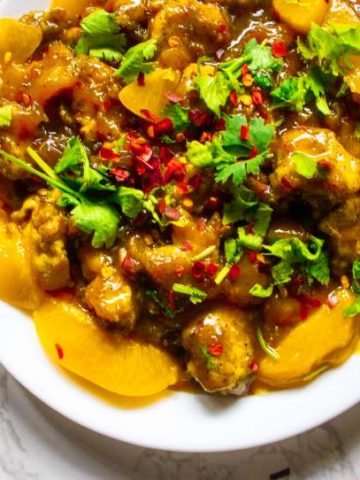 peach chicken in a plate with red pepper flakes and parsley