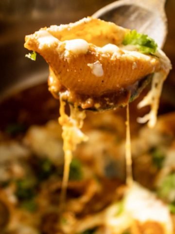 stuffed shell on a spatula with cheese pull beneath