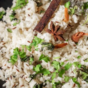 jeera rice served on a black plate with coriander and star anise