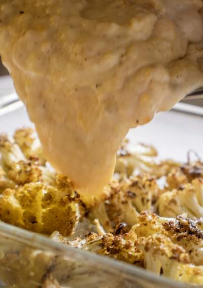 pouring cheese sauce on cauliflower