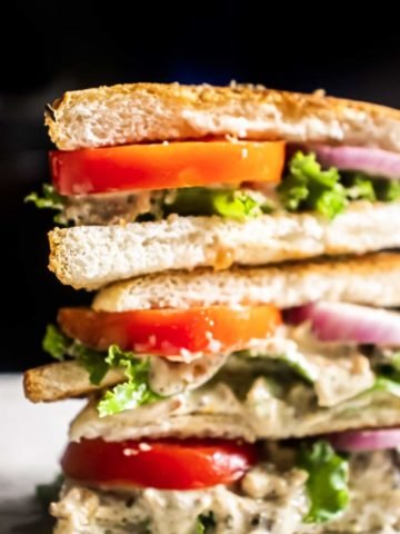 salmon salad sandwich on a white table with black background