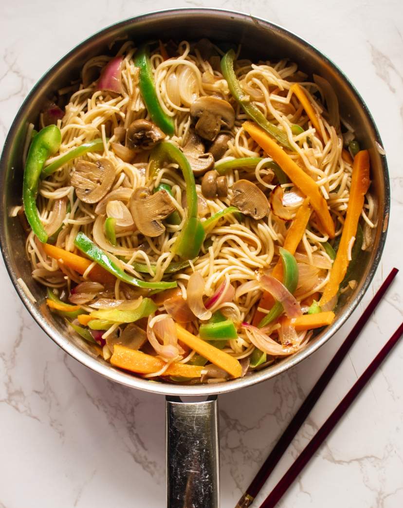 Vegetable Chow Mein in a skillet with two chopsticks beside it