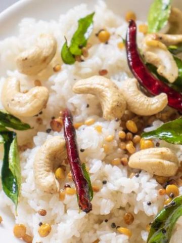 coconut rice with curry leaves cashews and dried red chilies in a white bowl