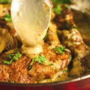 pouring marsala sauce on chicken with a spoon