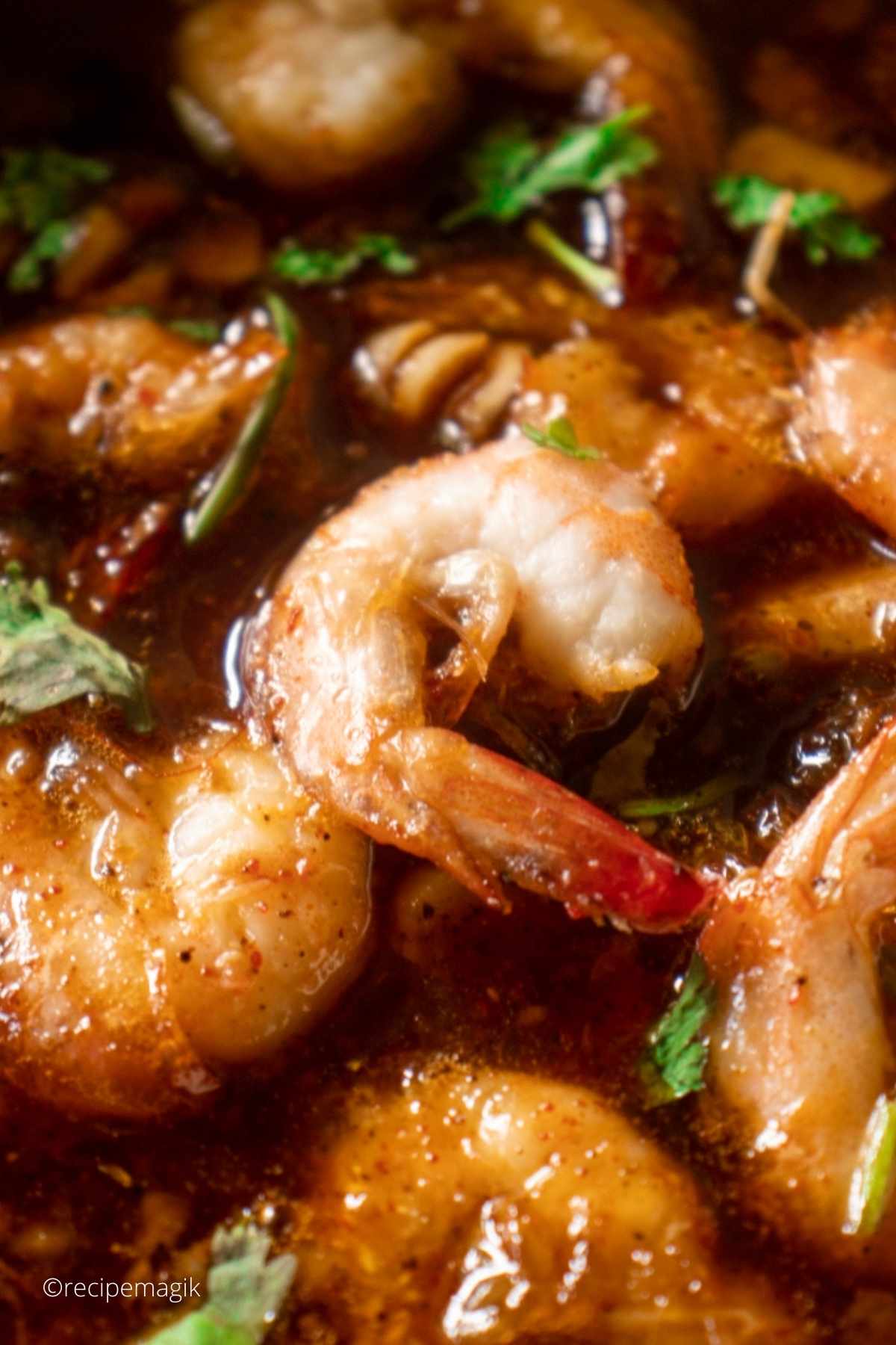 closeup of one shrimp in spicy sauce garnished with fresh parsley