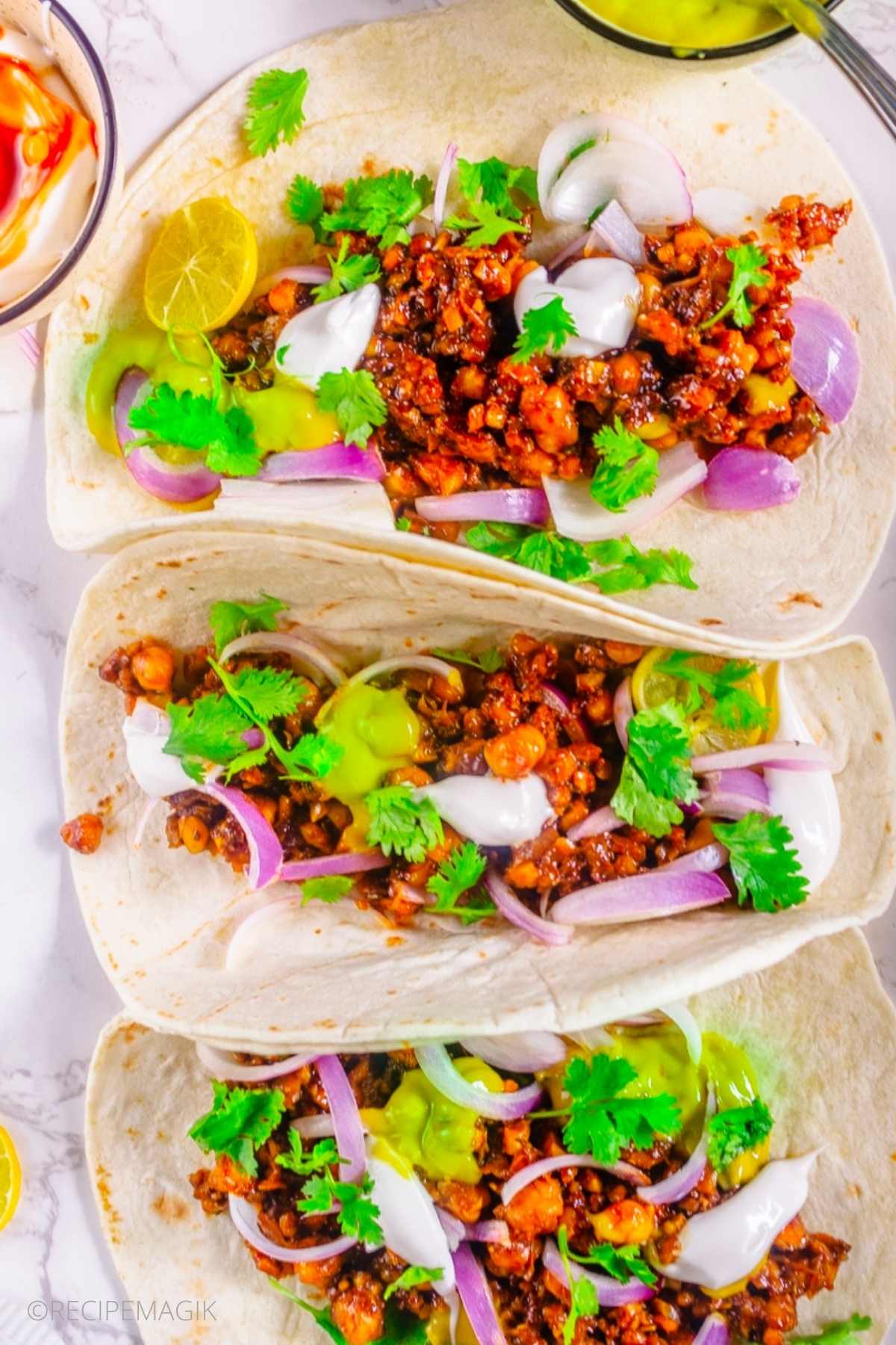 Vegan Chickpea Walnut Tacos on a white table with red onions and cilantro
