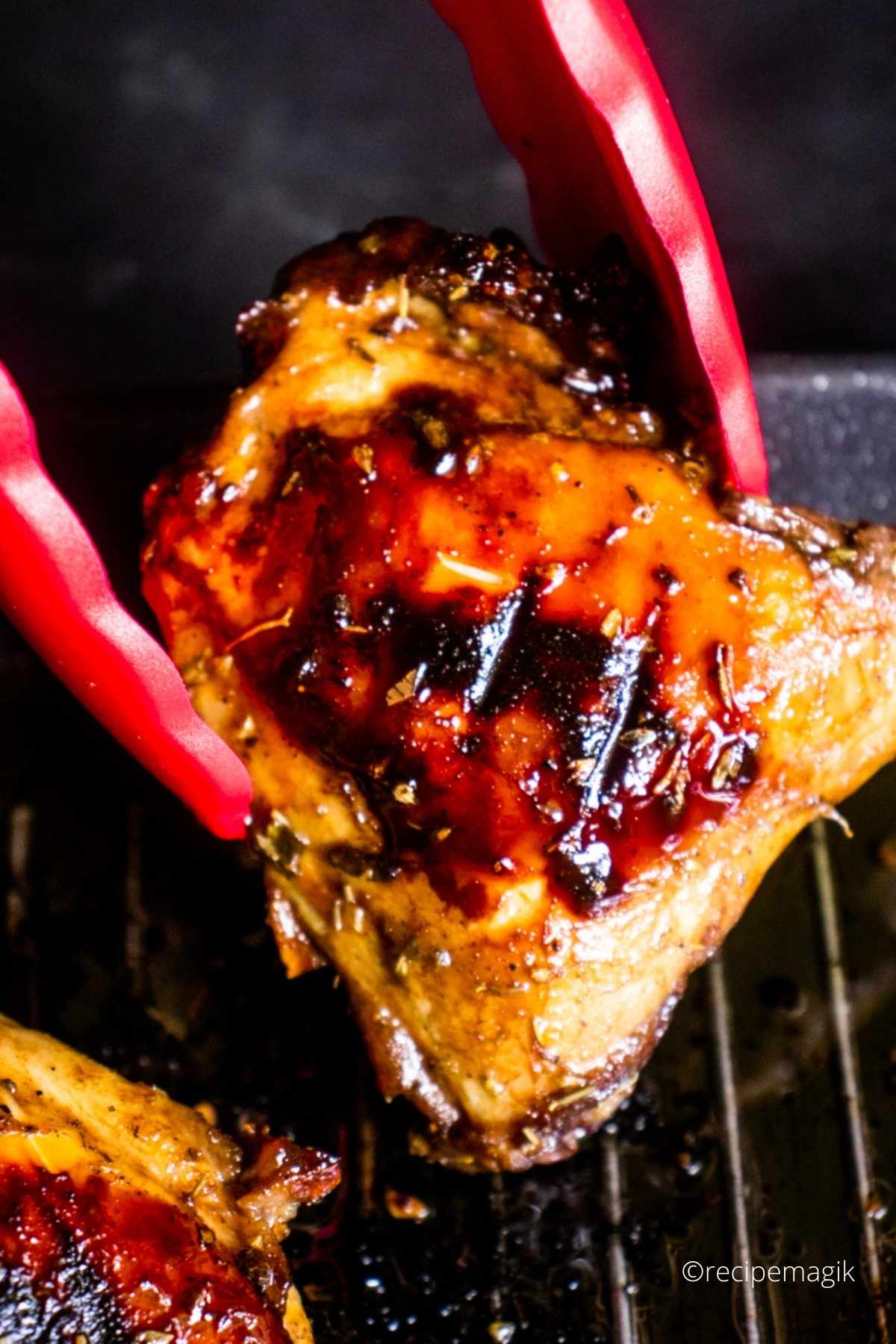 kitchen tongs holding on balsamic grilled chicken thigh