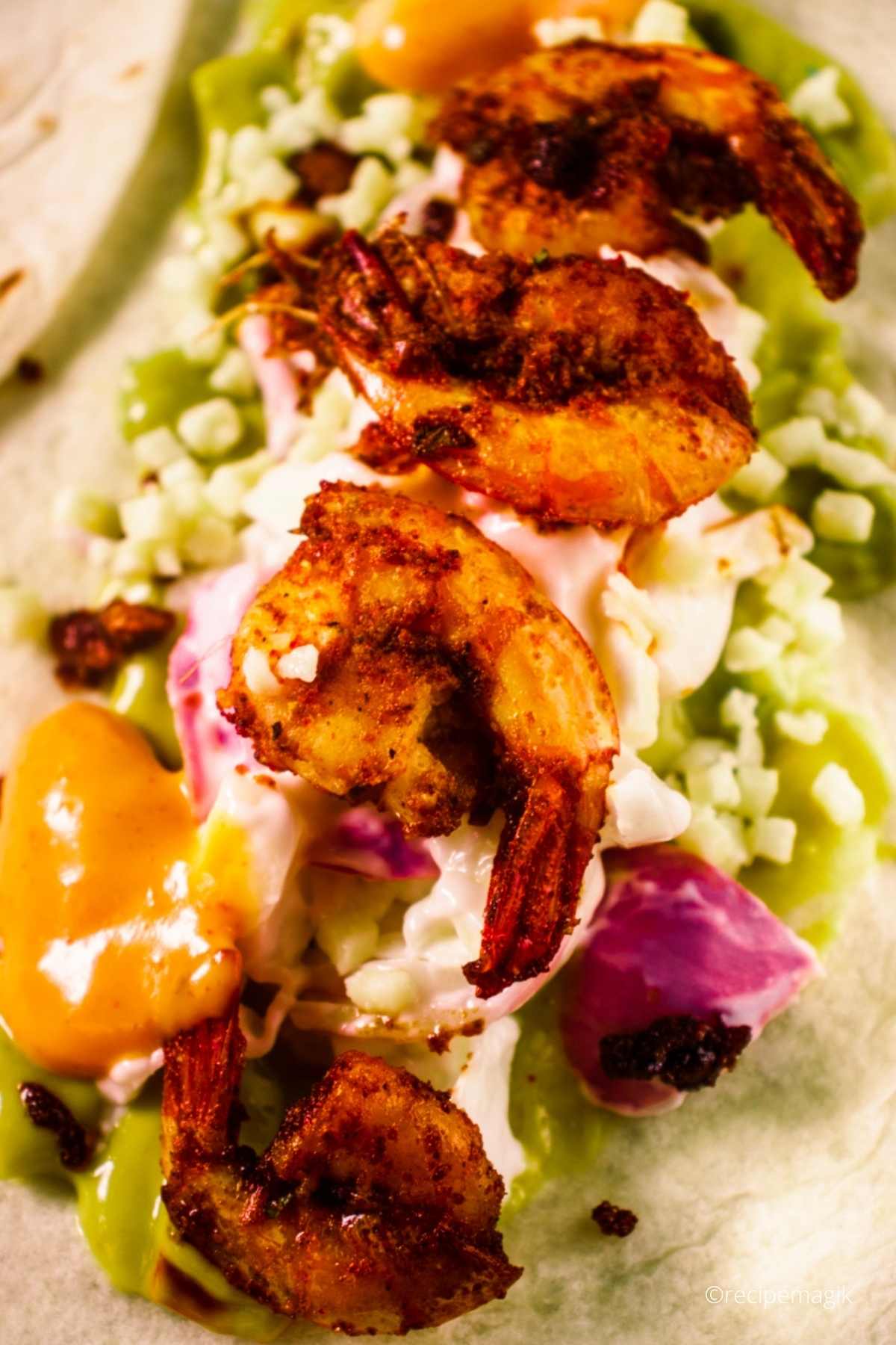 blackened shrimps arranged in a taco with guacamole